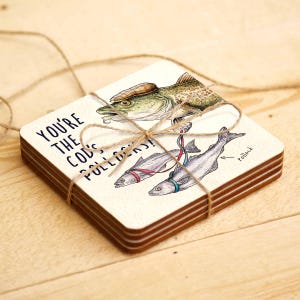May include: Set of four coasters featuring a humorous illustration of a cod fish wearing a hat and pulling two smaller fish with a string. The text on the coaster reads "You're the cod's bolloxs!"