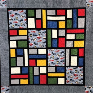 May include: A quilt with a geometric design featuring squares and rectangles in various colors, including red, yellow, blue, green, and gray. The squares and rectangles are arranged in a grid pattern, and the quilt is made with a variety of fabrics.