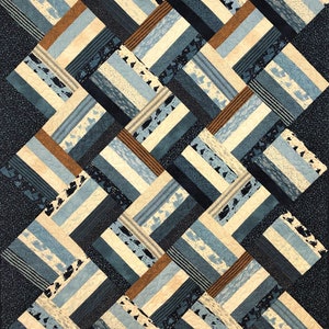 May include: A quilt with a geometric pattern of blue, brown, and white fabric squares. The squares are arranged in a diagonal pattern, creating a sense of movement and depth.