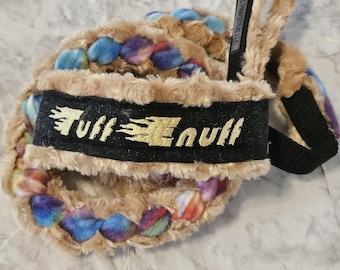 May include: A braided pet lead featuring tan faux fur wrapped around a multi-coloured core of blue, purple, and red fibres. A black fabric handle section displays the gold embroidered text Tuff Enuff and a small tag reading All Pawsitive LLC.