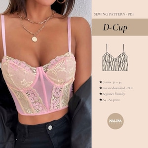 Pode incluir: Um top de corset D-Cup rosa e bege com detalhes em renda e alças finas. A imagem inclui o texto "SEWING PATTERN PDF" e "D-Cup". Texto adicional indica tamanhos 32-44, download instantâneo, para iniciantes e impressão A4/Ao.