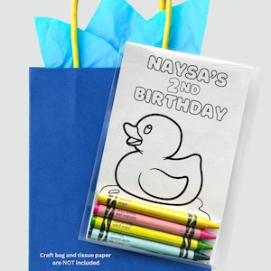 May include: A blue gift bag with yellow handles and blue tissue paper. A clear plastic bag contains crayons and a coloring page with a duck design and the text "Naysa's 2nd Birthday".