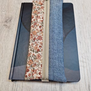 Op de afbeelding: Een etui met rits met een bloemenprint aan de ene kant en denim stof aan de andere kant.