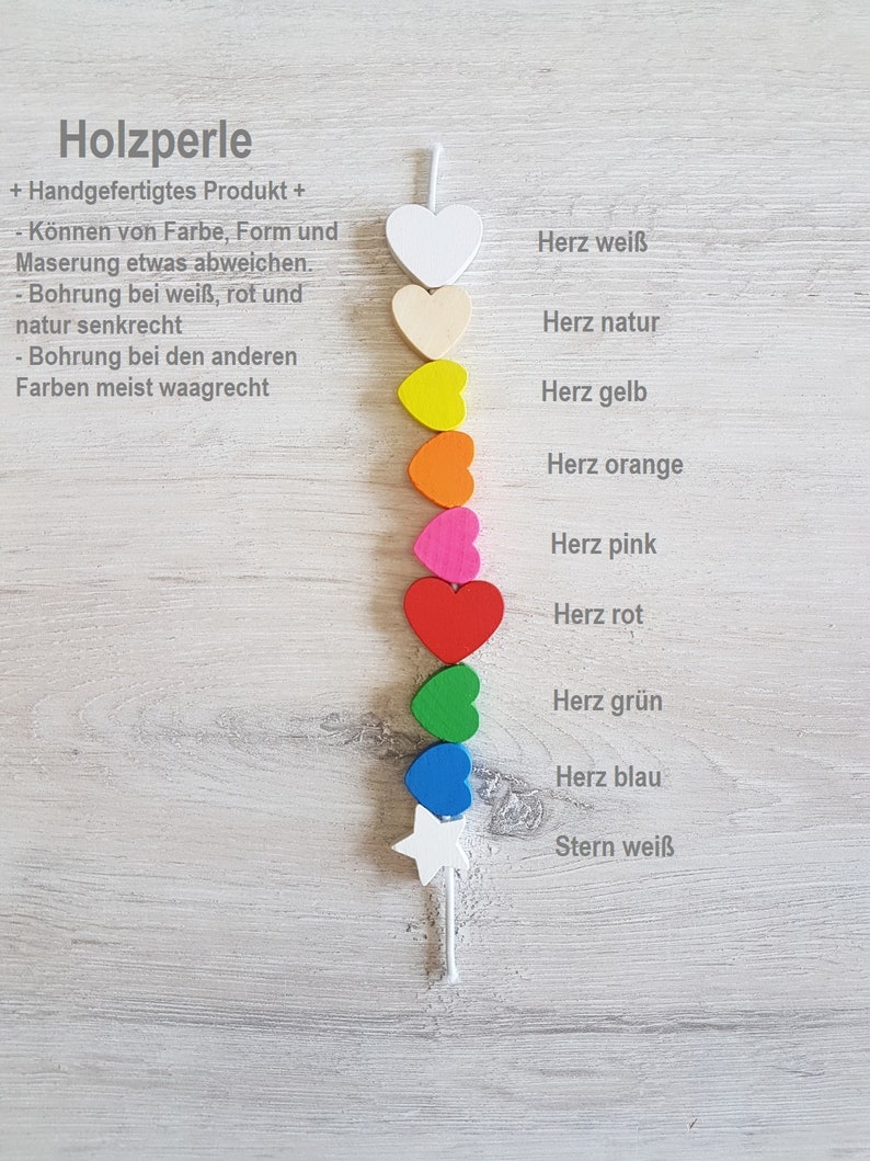 May include: A string of wooden heart-shaped beads in various colours, including white, natural, yellow, orange, pink, red, green, and blue. The beads are strung on a white cord and are arranged in a vertical line. The last bead is a white star. The text "Holzperle" is visible at the top of the image.