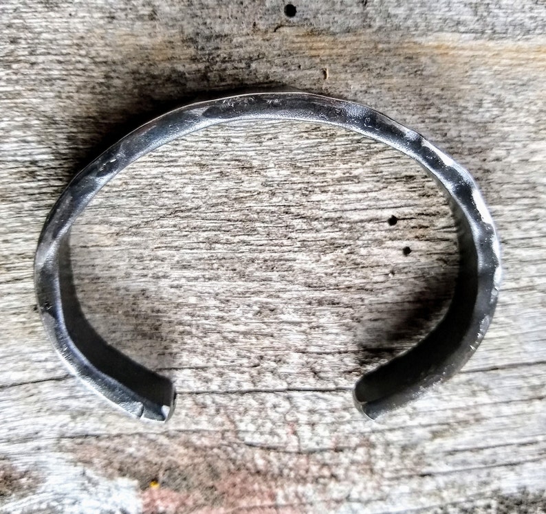 May include: A silver metal bracelet with a hammered finish.