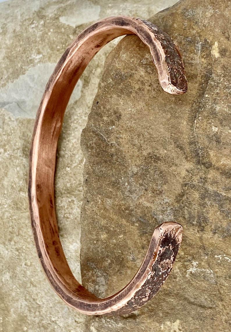 K&ouml;nnte beinhalten: Ein geh&auml;mmertes Kupferarmband mit rustikalem Finish. Das Armband ist offen und hat eine leicht gebogene Form.