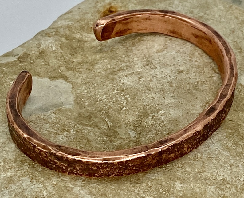 K&ouml;nnte beinhalten: Ein geh&auml;mmertes Kupferarmband mit rustikalem Finish. Das Armband ist offen und hat ein schlichtes Design.
