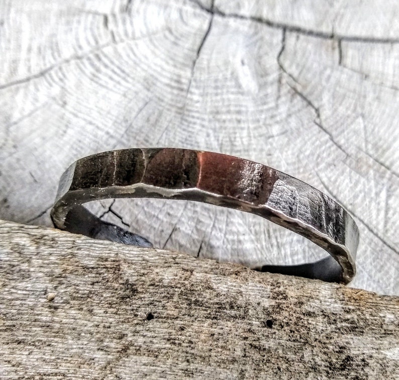 May include: A silver hammered metal bracelet with a slightly rounded shape.