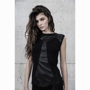 May include: Black sleeveless top with geometric faux leather panels. The top features a crew neck and a fitted silhouette. The design incorporates a mix of textures, with smooth fabric and textured faux leather accents. The overall style is modern and edgy.