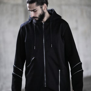 May include: A black zip-up hoodie with a long, asymmetrical hemline and zipper detailing on the sleeves.