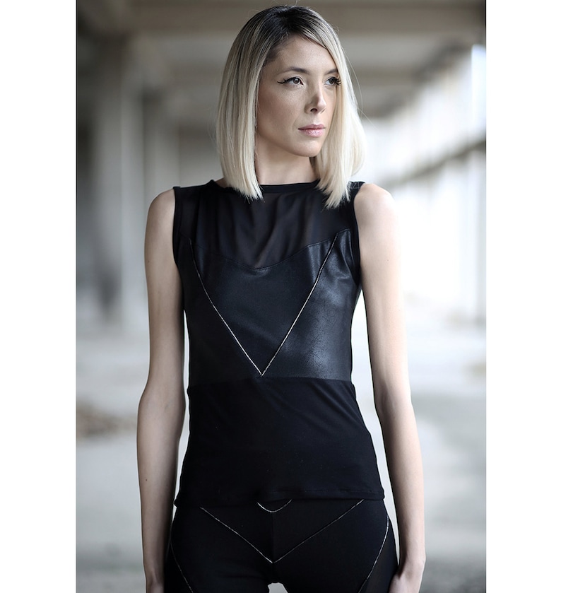 Op de afbeelding: Een zwart tanktop met een mesh-paneel en een kunstleren overlay. De overlay heeft een geometrisch ontwerp met witte stiksels.