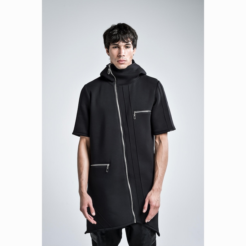 Puede incluir: Chaqueta negra de manga corta con cuello alto y capucha. La chaqueta presenta una cremallera plateada diagonal y dos bolsillos con cremallera. El dise&ntilde;o tiene una est&eacute;tica moderna y atrevida.