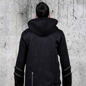 May include: A black hooded sweatshirt with zipper detailing on the sleeves and a diagonal zipper on the side. The sweatshirt has a relaxed fit and a long, asymmetrical hem.