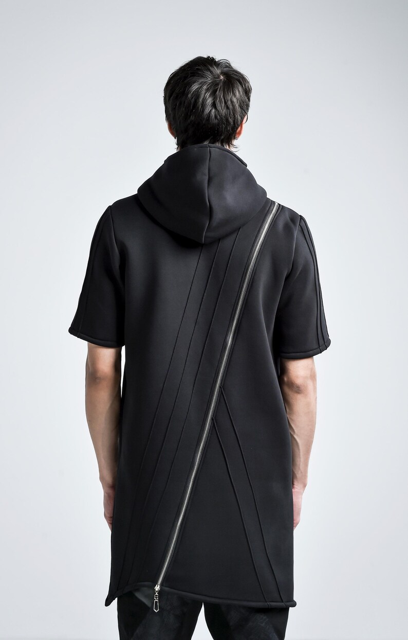 Puede incluir: Sudadera con capucha negra de manga corta con cremallera plateada diagonal. La sudadera tiene capucha y detalles de costura verticales en la parte delantera y trasera. El modelo est&aacute; de espaldas.