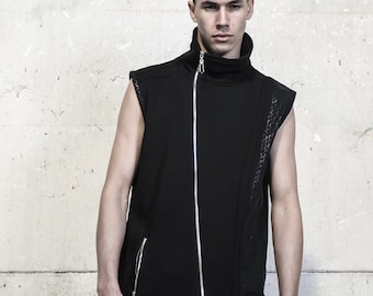 May include: Sleeveless black vest with a high collar and a diagonal silver zipper. The vest features quilted panels on the shoulders and side, paired with black pants. The outfit is a modern, edgy style.