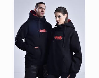 May include: Two people wearing black hoodies with red lining and a red embroidered design. The hoodies have a front pocket and a drawstring hood. The design on the front of the hoodie says "KILL ROSE".