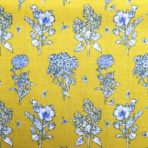May include: A yellow fabric with a repeating pattern of blue flowers. The flowers are in various styles, including clusters of small flowers, single large flowers, and clusters of bell-shaped flowers.