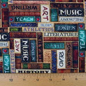 May include: Fabric featuring a repeating pattern of books with educational terms such as "Music", "Math", and "History". The books are in various colours, including brown, green, and blue, with red apple accents. The fabric is measured with a wooden ruler.