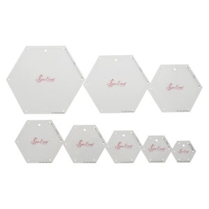 May include: Set of eight white plastic hexagon quilting templates with a pink "Sew Easy" logo. The templates range in size from 1.5 inches to 6 inches.