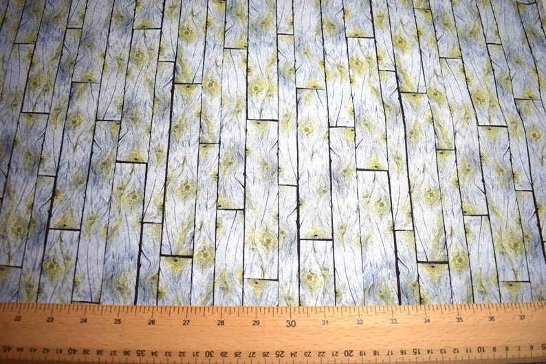 May include: Fabric with a wood plank design. The pattern features vertical planks in shades of gray and white, with yellow accents in the wood grain. The fabric is suitable for various craft projects.