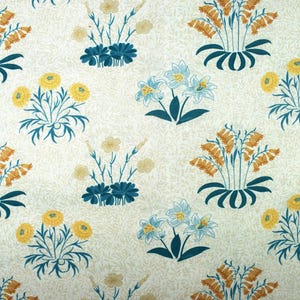 Peut inclure: Tissu crème avec un motif floral répété. Le motif présente des bouquets stylisés de fleurs jaunes, orange et bleues avec des feuilles et des tiges vert teal foncé. Le fond a un aspect subtil et texturé.
