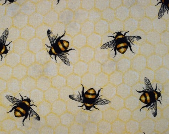 May include: A yellow fabric with a honeycomb pattern and multiple black and yellow bees printed on it.