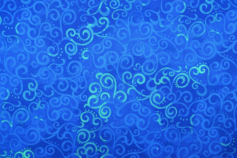 May include: A close-up of a blue fabric with a swirling, ornate pattern. The design features light blue and teal-colored curls and dots against a deep blue background. The fabric has a textured appearance.