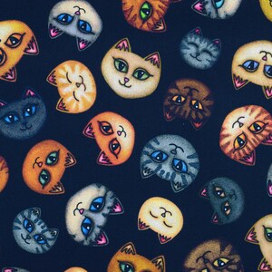 May include: A dark blue fabric with a repeating pattern of colourful cat faces. The cats have different expressions and colours, including orange, brown, grey, and white.