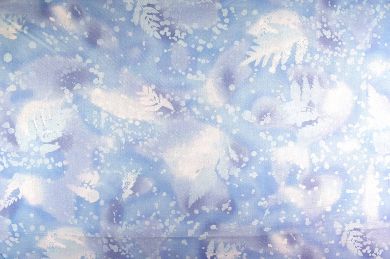 May include: A fabric with a watercolor-like design in shades of blue and white. The pattern features abstract shapes, dots, and leaf-like silhouettes, creating a soft, ethereal aesthetic. The overall effect is reminiscent of a winter scene.