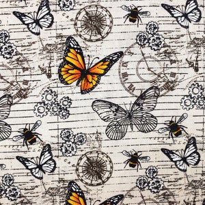 May include: A beige fabric with a repeating pattern of butterflies, bees, and gears. The butterflies are in shades of black, white, and orange. The bees are black and yellow. The gears are black and white. The background is a beige fabric with a distressed look.