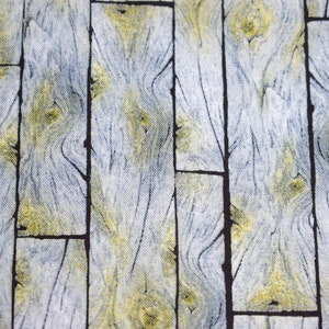 May include: Close-up of a fabric with a wood grain pattern. The design features vertical planks in shades of gray, yellow, and black. The fabric has a textured appearance, with the wood grain details clearly visible.