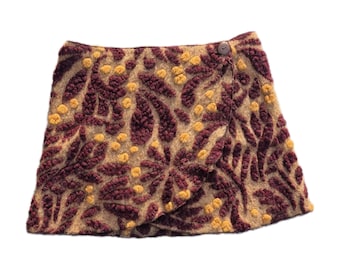 May include: A brown and mustard yellow wrap skirt with a floral pattern. The skirt has a single button closure.