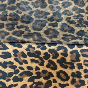 May include: A close-up of two pieces of fabric with a leopard print pattern. The top piece is a sheer mesh fabric, while the bottom piece is a solid fabric.