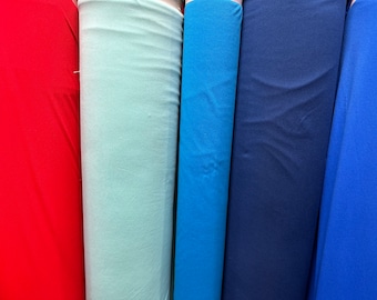 May include: Five rolls of fabric in different colors: red, light blue, blue, dark blue, and royal blue. The fabric is smooth and appears to be a knit material.