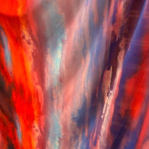 May include: Abstract fabric with a watercolor-like design in shades of red, blue, and pink. The fabric has a flowing, ethereal quality.