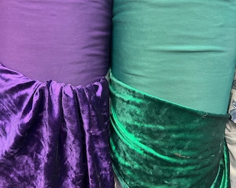 May include: Two rolls of fabric, one purple and one green. The purple fabric is a velvet with a soft, plush texture. The green fabric is a smooth, silky material.