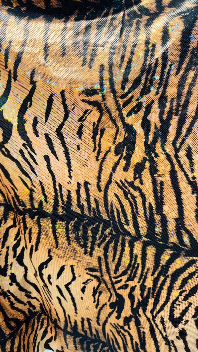 Puede incluir: Primer plano de una tela de estampado de tigre marr&oacute;n y negro con un acabado brillante.