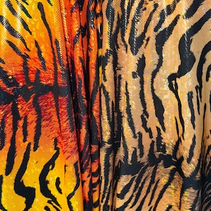 Puede incluir: Primer plano de una tela con un patr&oacute;n de rayas de tigre en naranja, negro y amarillo. La tela tiene un acabado brillante e iridiscente.