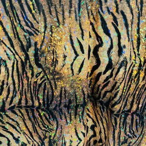 May include: Close-up of a brown and black fabric with a tiger stripe pattern. The fabric is covered in iridescent glitter.