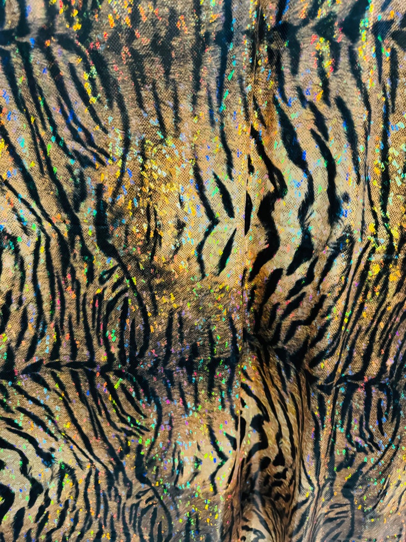 May include: Close-up of a brown and black fabric with a tiger stripe pattern. The fabric is covered in iridescent glitter.