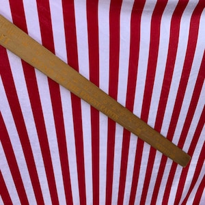 May include: Red and white striped fabric with a wooden ruler measuring 36 inches. The ruler has the words "Made in West Paris" printed on it.
