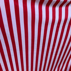 May include: Red and white striped fabric with a subtle sheen. The fabric is folded and the stripes are angled.