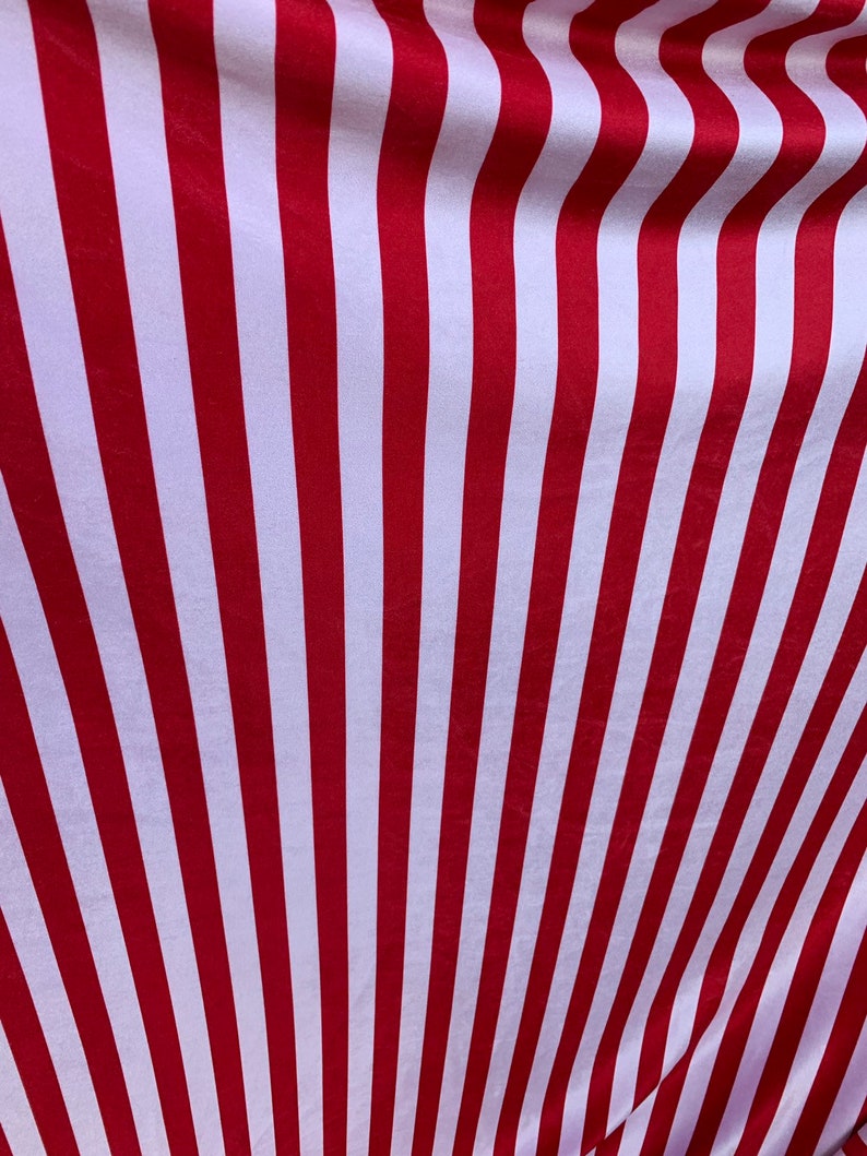 May include: Red and white striped fabric with a subtle sheen. The fabric is folded and the stripes are angled.