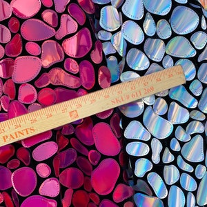 May include: Close-up of iridescent fabric with a pattern of sewn-on, rounded shapes. The fabric is black with pink and silver holographic shapes. A ruler is visible with the text "PAINTS" and "SKU# 611 269".