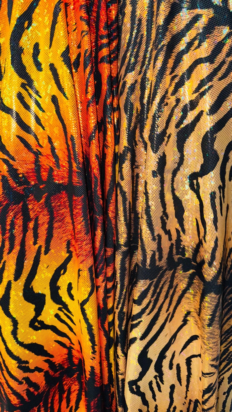 Puede incluir: Primer plano de una tela con estampado de tigre. La tela es naranja, negra y amarilla con un acabado brillante.