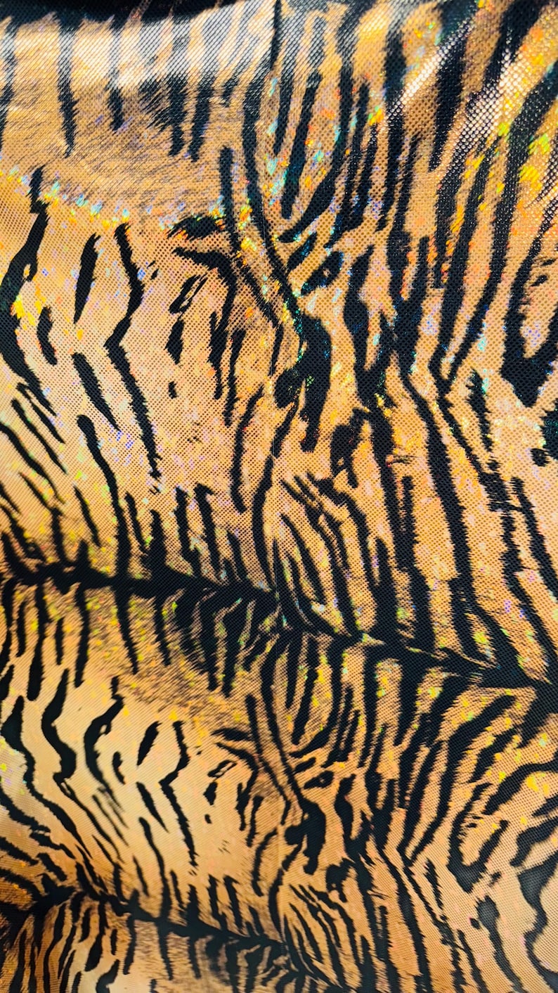 Puede incluir: Primer plano de una tela de estampado de tigre con un acabado brillante e iridiscente. La tela tiene un patr&oacute;n de rayas de tigre negras y naranjas.