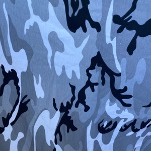 May include: A close-up of a grey and black camouflage pattern fabric. The fabric has a soft, textured feel and is ideal for creating unique clothing or accessories.