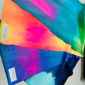 May include: Five fabric swatches with tie-dye patterns in shades of blue, pink, orange, yellow, and green. The swatches are labeled with the color names: "Navy Grey", "Hot Pink/Blue", "Orange/Yellow", and "Multi Pastel".