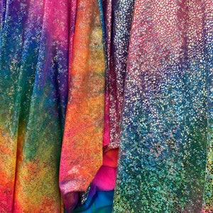K&ouml;nnte beinhalten: Drei irisierende Stoffe mit einem Regenbogen-Farbverlauf. Der Stoff links hat einen Batik-Effekt, der Stoff in der Mitte hat eine schimmernde Oberfl&auml;che und der Stoff rechts hat eine strukturierte, irisierende Oberfl&auml;che.