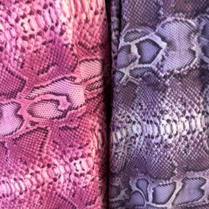 Könnte beinhalten: Ein Stoff mit Schlangenhautmuster in zwei verschiedenen Farbbereichen. Die linke Seite zeigt einen leuchtenden Magenta- und Rosaton, während die rechte Seite einen gedämpften Violett- und Lavendelverlauf aufweist, beide mit detaillierter Schuppenstruktur.